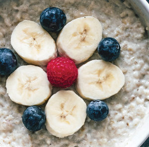 bowl of oatmeal dressed with bananas blueberries and raspberries
