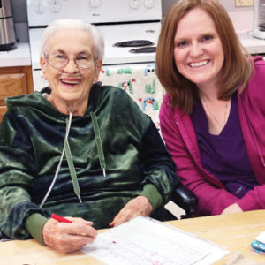 Older adult woman sitting with adult woman at table smiling for photo